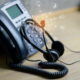 A VoIP phone and headset on a desk with digital icons overlay, illustrating the importance of VoIP technology in supporting business continuity in Dallas.